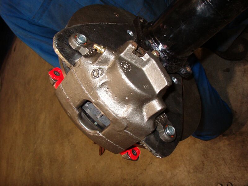 Bare cast disc brake caliper mounted to an axle bracket during a disc conversion