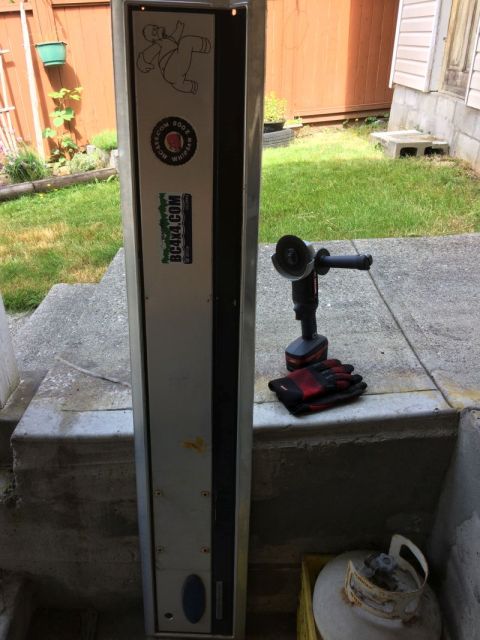 1985 Ford Bronco - A cordless angle grinder and work gloves are resting on a concrete ledge next to a tall metal cabinet with stickers on it. A propane tank i…