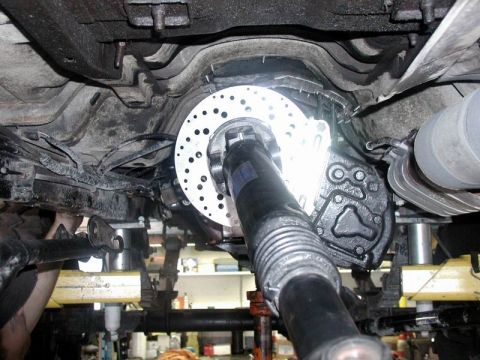 1985 Ford Bronco - Underside view of a vehicle's rear axle assembly, showing a newly installed disc brake rotor and caliper mounted to the driveshaft.