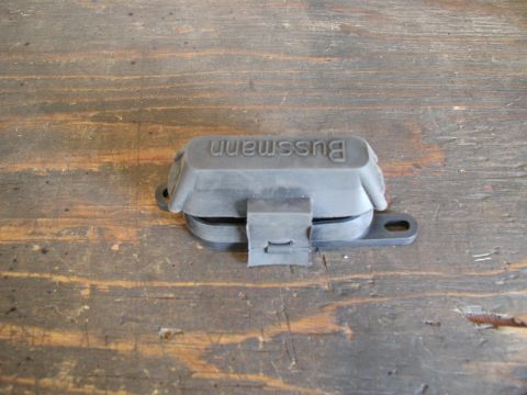 1985 Ford Bronco - A black Bussmann fuse holder with a rubber cover is shown resting on a weathered wooden surface. The fuse holder has a clip closure and mou…