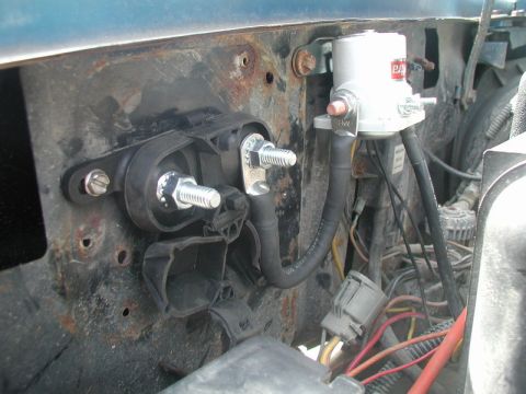 1985 Ford Bronco - A close-up view of electrical components mounted to a rusty metal surface, likely in an engine bay. Visible parts include a silver solenoid…