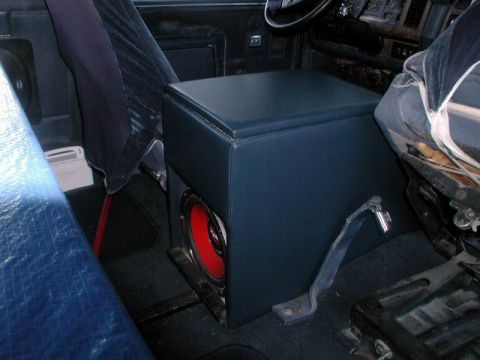 1985 Ford Bronco - Custom blue vinyl-wrapped center console box built between the seats of a truck, with a red-cone subwoofer mounted in a cutout on its lower…