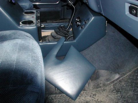 1985 Ford Bronco - Blue vinyl center console panels laid loose on the passenger floor of a truck during a trial fit, with the console's cup-holder top and a s…