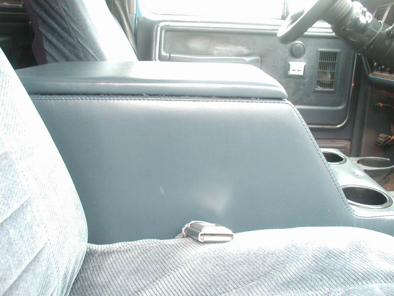 Blue vinyl center console with chrome latch and cup holders in truck