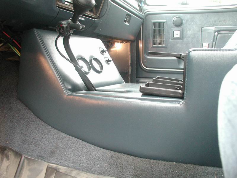 Blue vinyl console with two empty gauge holes and chrome switches in a Bronco