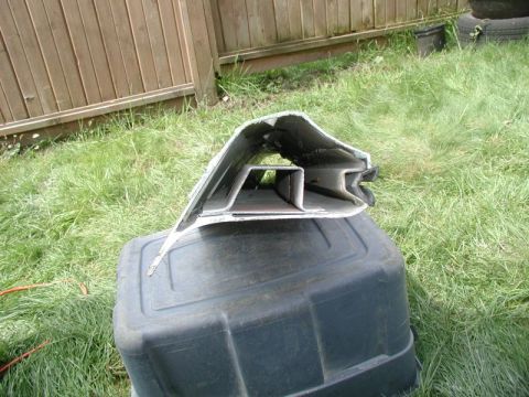 1985 Ford Bronco - A damaged, possibly aftermarket, metal bumper or body panel is resting on a black plastic container outdoors. The panel appears to be silve…