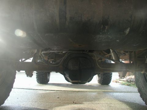 1985 Ford Bronco - Underside view of a vehicle's rear differential and suspension components, with large off-road tires visible.