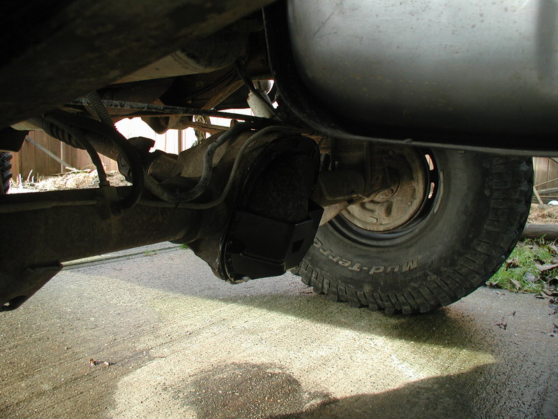 Rear differential with skid plate and tire on a vehicle.