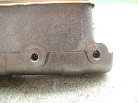 1985 Ford Bronco - A close-up view of the side of a cast metal component, likely a master cylinder, showing two threaded ports with brass fittings.