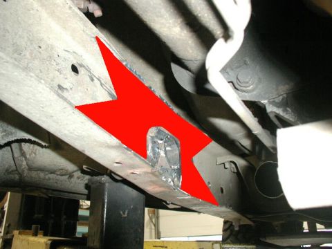 1985 Ford Bronco - The underside of a vehicle frame shows a section that has been cut out and reinforced with metal plating. A red arrow highlights the modifi…