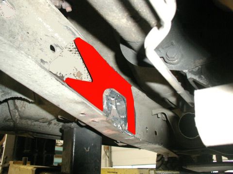 1985 Ford Bronco - A red-highlighted metal brace is welded onto the frame of a vehicle, likely for reinforcement. The vehicle appears to be on a lift in a gar…