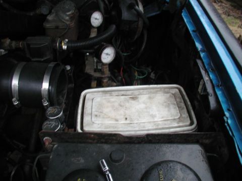 1985 Ford Bronco - The image shows a close-up view of an engine bay, likely from a 1985 Ford Bronco, with various components visible including a large black i…