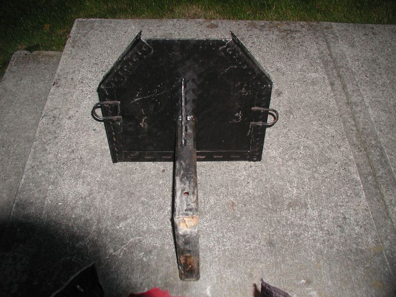 Black metal grill or cooking grate with a handle on concrete