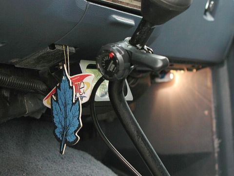 1985 Ford Bronco - A blue leaf-shaped air freshener hangs from the dashboard of a vehicle, obscuring a portion of the steering column and a black lever. The a…