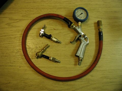 1985 Ford Bronco - A set of air tools including an air pressure gauge, a blow gun, and two tire chucks are arranged on a wooden surface.