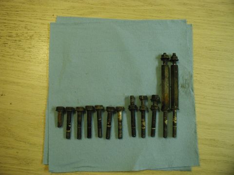 1985 Ford Bronco - A collection of bolts and threaded rods are laid out on a light blue shop towel, which is on a wooden surface.