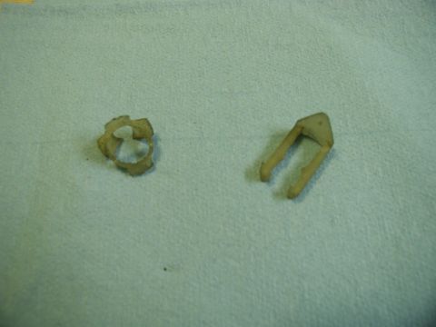 1985 Ford Bronco - Two small, beige plastic automotive clips are shown on a light blue textured surface. One clip is circular with serrated edges, and the oth…