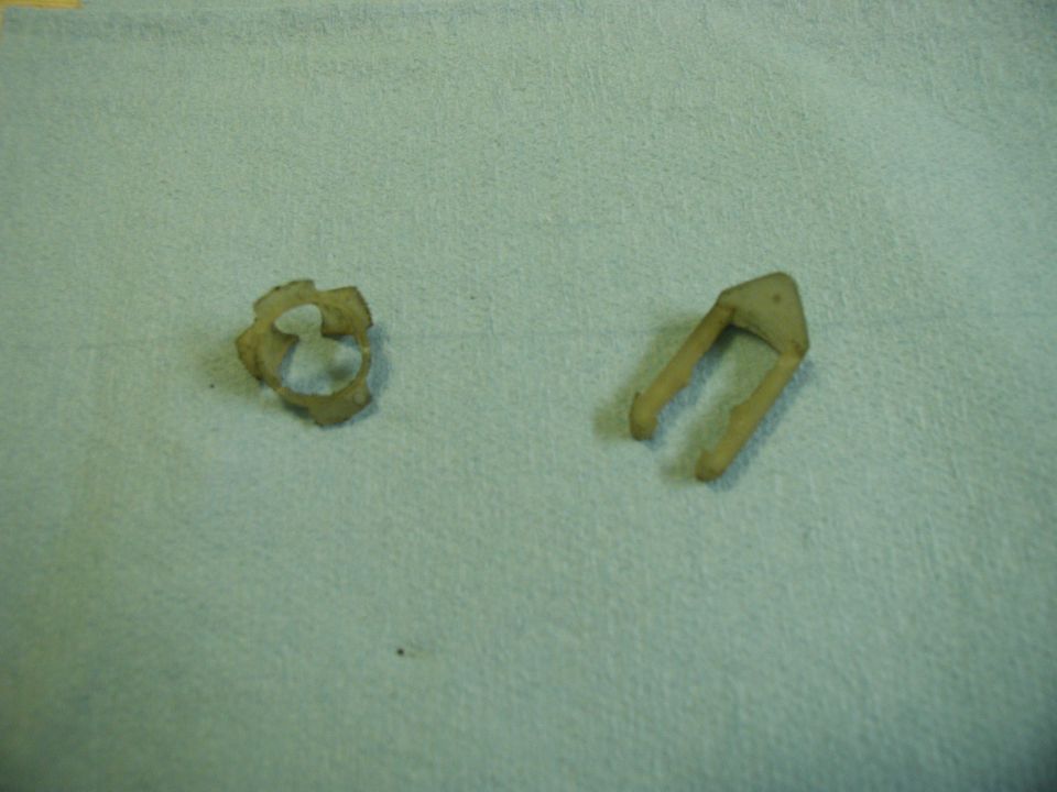Two beige plastic automotive clips on a blue textured surface.