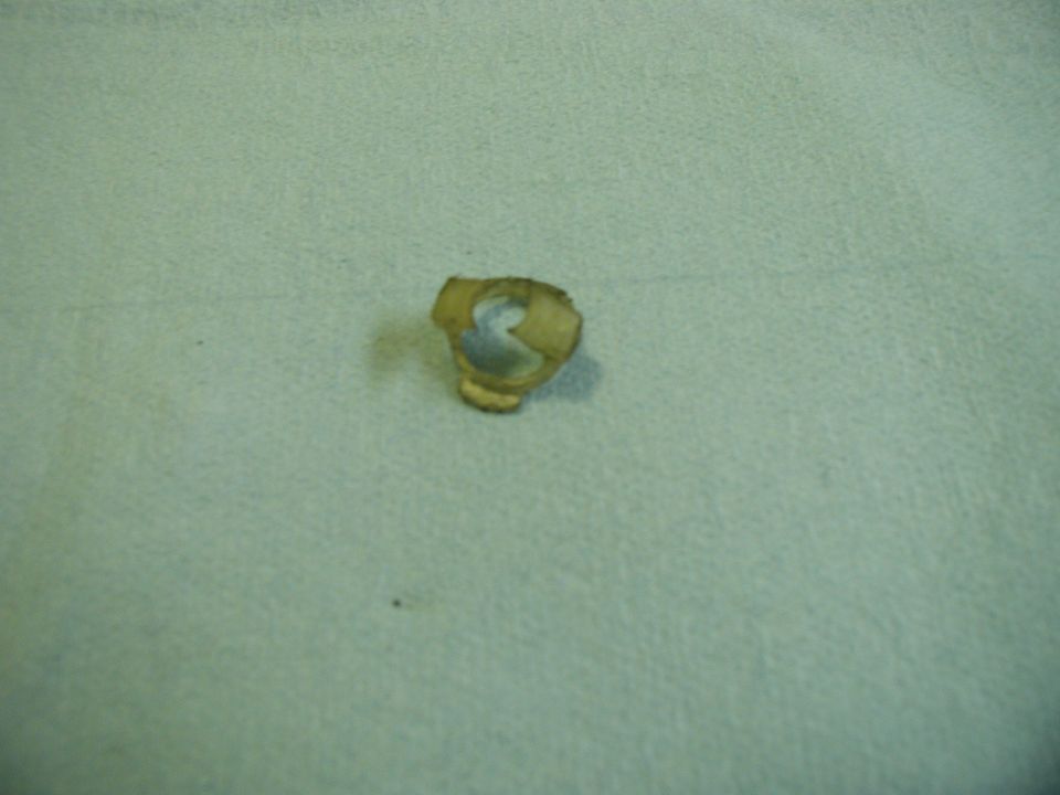 A small, bent piece of metal on a textured surface.