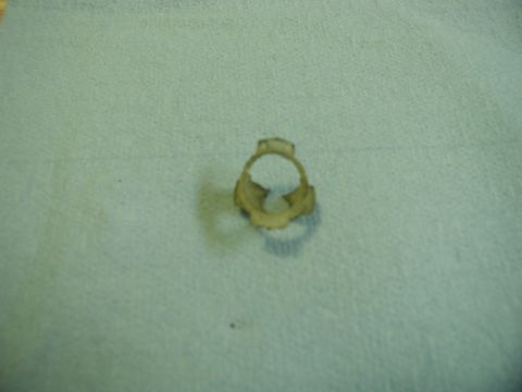 1985 Ford Bronco - A small, light-colored metal hose clamp is shown against a textured light blue background. The clamp has a circular shape with two prongs e…