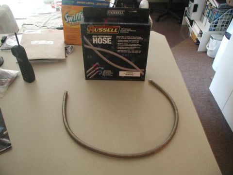 1985 Ford Bronco - A Russell High-Performance Hose is shown on a table next to its packaging. A cordless phone and a box of Swiffer Dusters are also visible.