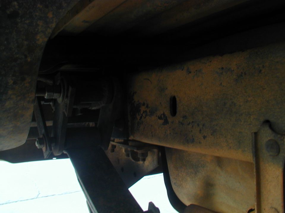 Undercarriage view of rusty frame and suspension components