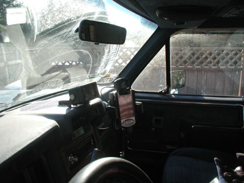 1985 Ford Bronco - Interior view of a vehicle's dashboard, showing a rearview mirror, a GPS device mounted on the windshield, and a car stereo.