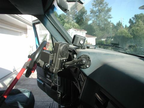 1985 Ford Bronco - Interior view of a modified vehicle dashboard, showing a custom steering wheel attachment and a mounted speaker or communication device.