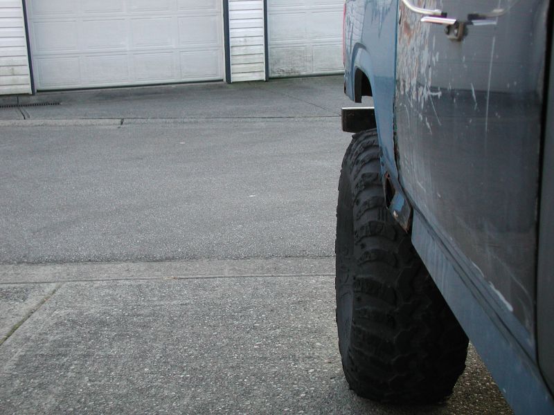 Side view of a blue vehicle's rear fender and large off-road tire.