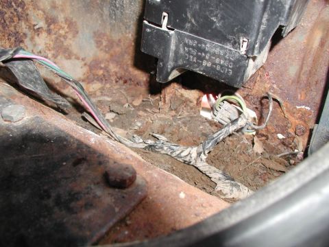 1985 Ford Bronco - A close-up view shows heavily rusted metal and wiring harnesses in what appears to be a vehicle's undercarriage or engine bay.