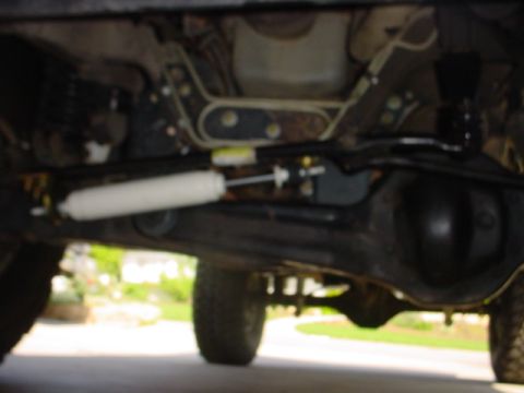 1988 Ford Bronco - The underside of a vehicle is visible, focusing on the steering stabilizer and rear axle components.
