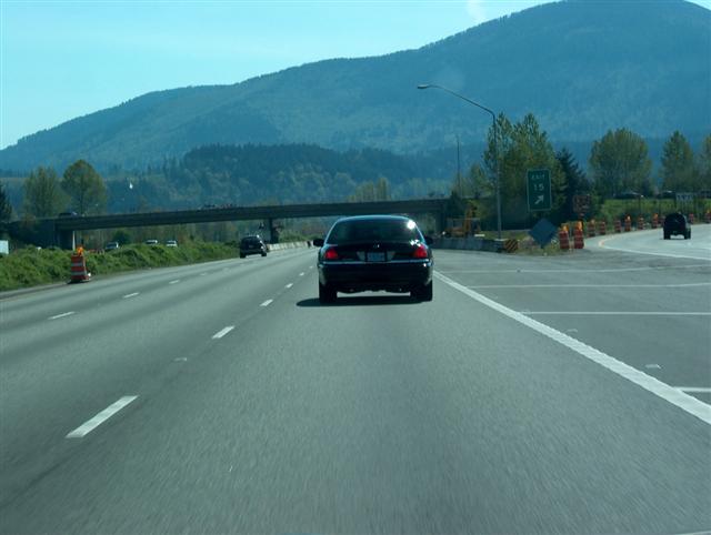 2001 Ford Crown Victoria driving on a highway with a mountain in the background
