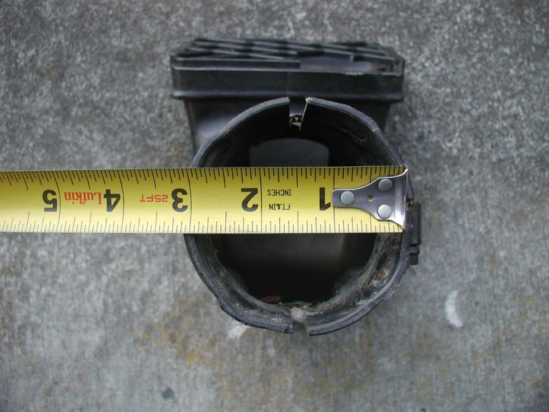 Yellow tape measure hooked on black snorkel tube rim on concrete