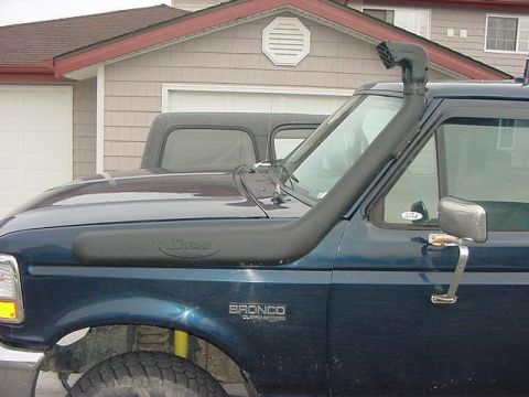1985 Ford Bronco - Passenger side of a dark blue Ford Bronco with a black Safari snorkel running along the fender and up the A-pillar to a raised ram head abo…