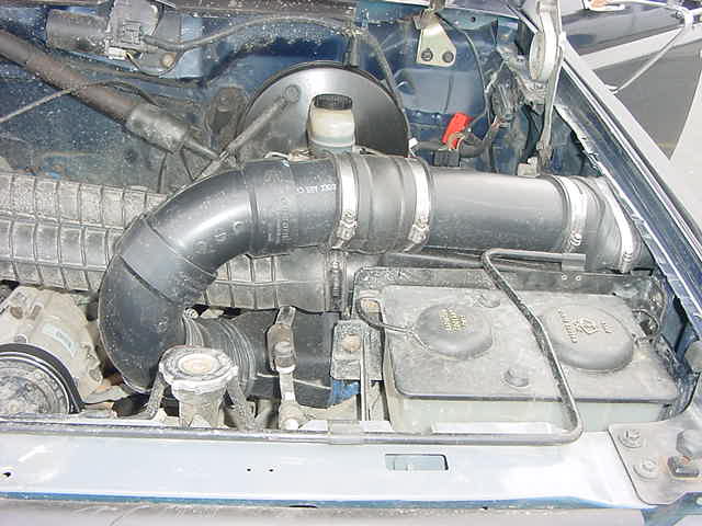 Engine bay with intake tube and fluid reservoirs