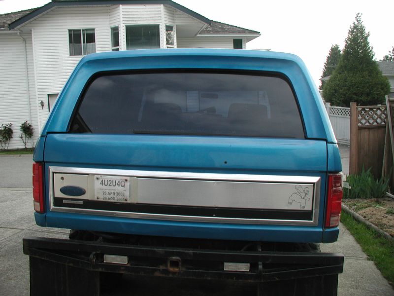 Rear view of teal blue Ford Bronco hardtop with 4U2U4Q plate in a driveway