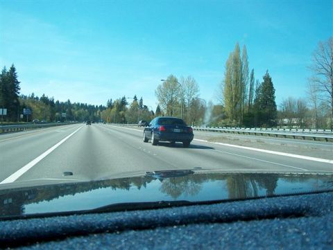 2001 Ford Crown Victoria - View from inside a vehicle driving on a multi-lane highway under a clear blue sky.