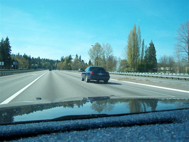 Driving on a highway with trees and other cars visible