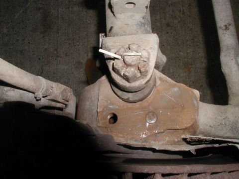 1985 Ford Bronco - A close-up view of a rusted automotive suspension component, likely a ball joint, with a cotter pin visible. The part is mounted on a vehic…