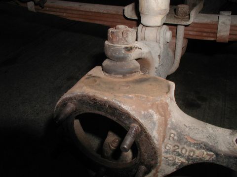 1985 Ford Bronco - A close-up view of a heavily rusted and dusty automotive suspension part, likely a spindle or knuckle, with a ball joint assembly attached.…