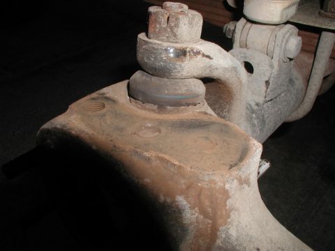 1985 Ford Bronco - A close-up, low-angle shot shows a heavily rusted ball joint assembly on what appears to be a vintage truck or SUV's suspension. The metal…