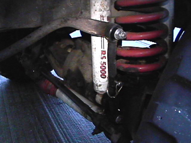 Vehicle suspension with red coil spring and R.S. 5000 shock absorber.