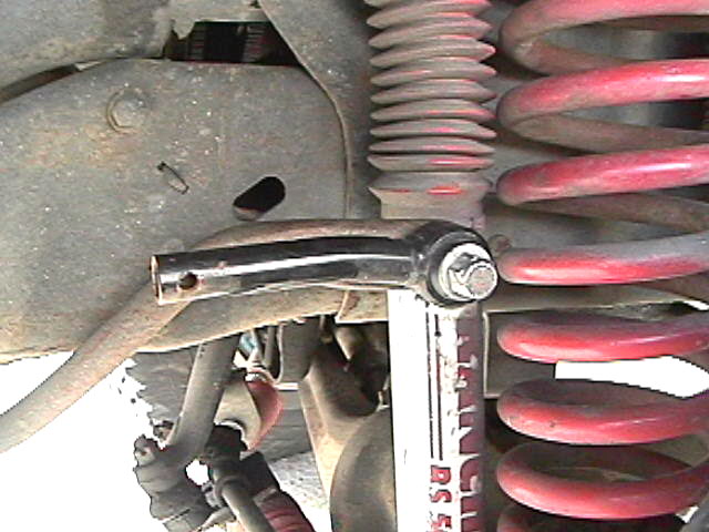 Vehicle suspension with red coil spring, shock absorber, and linkage.