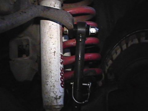 1985 Ford Bronco - A close-up view shows the suspension system of a vehicle, featuring a white shock absorber with red lettering and a red coil spring. A blac…