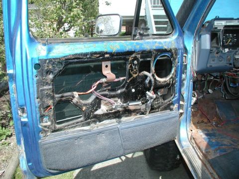 1985 Ford Bronco - The interior of a blue Ford truck or SUV with the driver's side door open, revealing the inner workings of the door panel and exposed wirin…