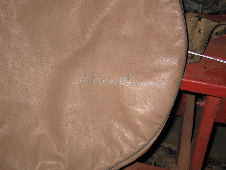 Close-up of a tan tire cover with 'Eddie Bauer' embroidered in cursive