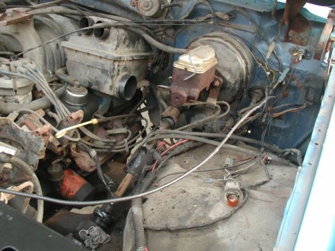 1985 Ford Bronco - The engine bay of a blue Ford Bronco is shown, with various components including the brake booster, master cylinder, air intake box, and wi…