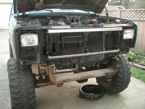 1985 Ford Bronco - Front view of a lifted, teal-colored Ford Bronco with its hood open, showing the engine bay and radiator. The front bumper and grille have…