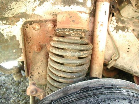 1985 Ford Bronco - A close-up view of the front suspension components of a vintage Ford Bronco, showing a rusty coil spring, shock absorber, and mounting hard…