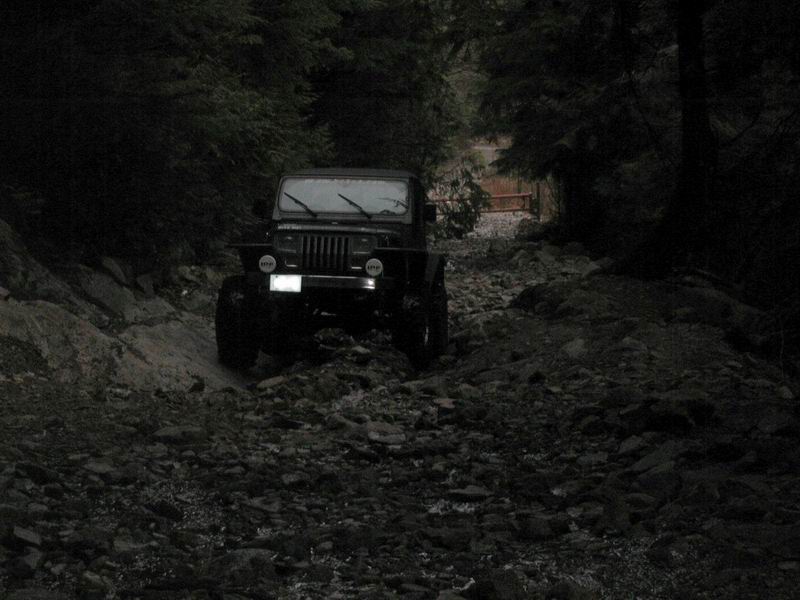 Jeep Wrangler on a rocky, wooded trail.